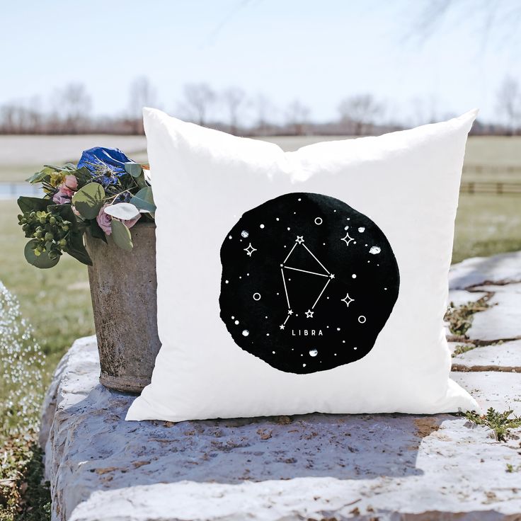 a pillow sitting on top of a stone wall next to a vase filled with flowers