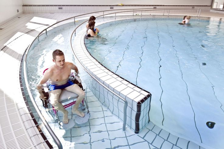 people are in the swimming pool and one person is sitting on an exercise wheel chair