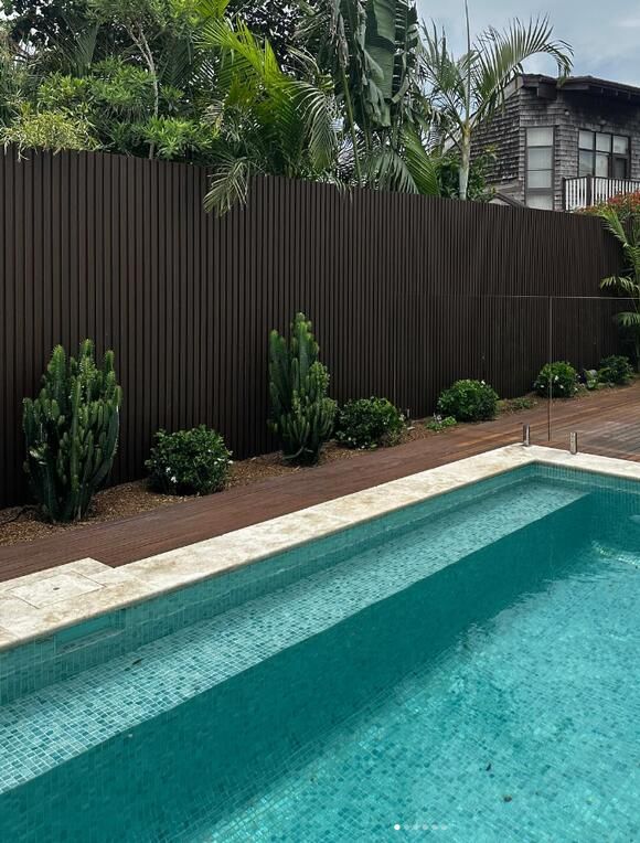 an empty swimming pool next to a wooden fence