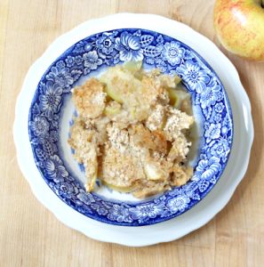 an apple buckle is served on a blue and white plate next to an apple