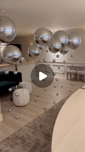 a living room filled with lots of silver balloons floating in the air over a wooden floor