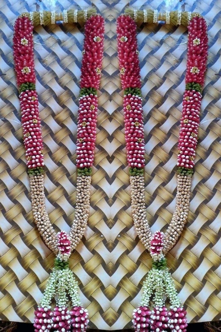 two red and white beaded necklaces are hanging on a wall next to each other