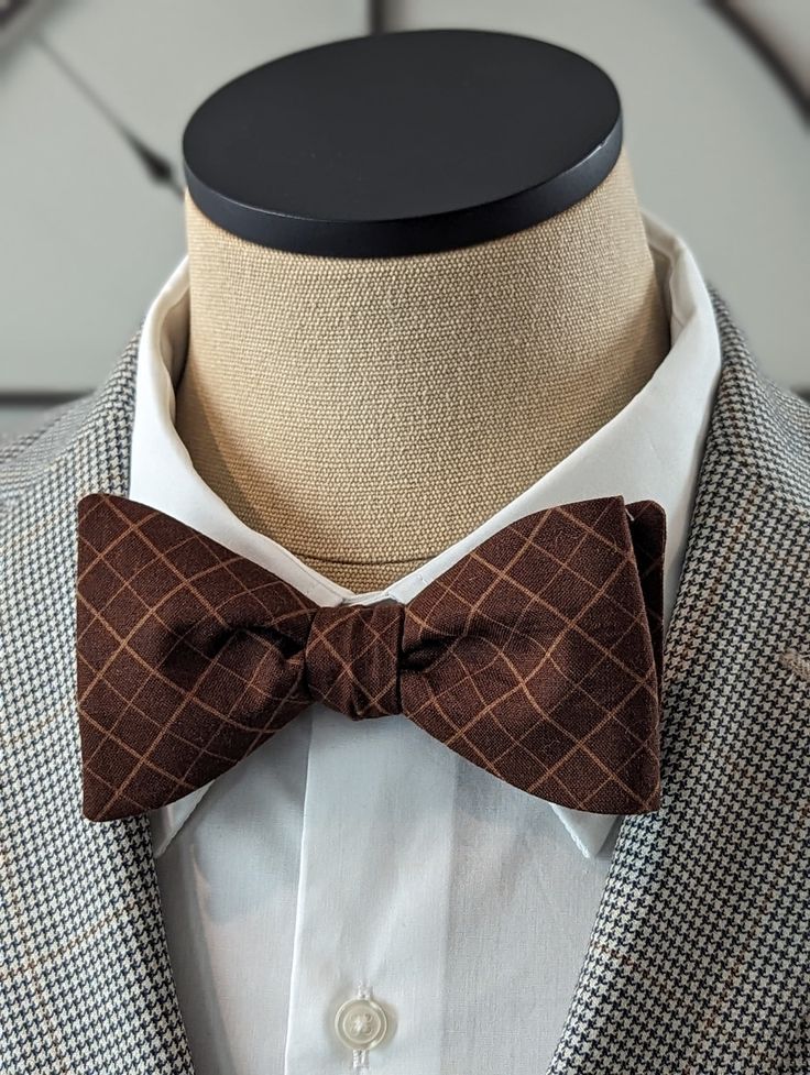 Elevate your style with this exquisite Brown Windowpane Bow Tie. Handcrafted with precision and attention to detail, this custom self-tie bow tie is the perfect accessory to add a touch of sophistication to your outfit. Featuring a classic stripe pattern, this bow tie is versatile and can be paired effortlessly with both casual and conservative attire. Whether you're attending a business meeting or a social event, this bow tie will instantly elevate your look and make a lasting impression. Made from high-quality materials, this Brown Windowpane Bow Tie is not only stylish but also durable, ensuring that it will last for years to come. The self-tie design allows for the perfect fit and gives you the freedom to adjust it according to your preference. With its timeless appeal, this bow tie is Classic Pre-tied Bow Tie, Classic Pre-tied Bow With Ties, Classic Pre-tied Decorative Bow, Classic Pre-tied Bow, Classic Pre-tied Tie With Decorative Bow, Classic Bow Tie For Suit Accessories As Gift, Classic Bow With Bow Tie Back, Classic Detachable Bow As A Gift, Elegant Brown Bow Ties