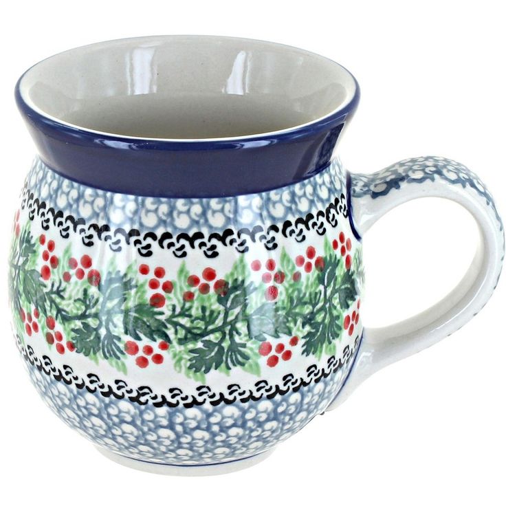 a blue and white mug with holly designs on it