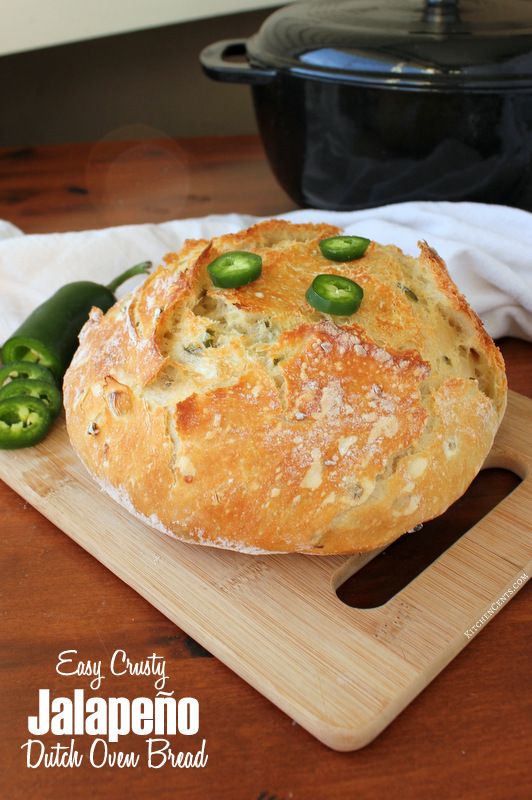 bread with jalapenos on a cutting board next to an open black dutch oven