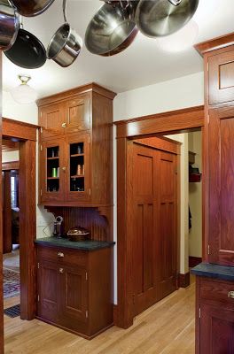 an open kitchen with wooden cabinets and hanging pots on the ceiling, along with black granite counter tops