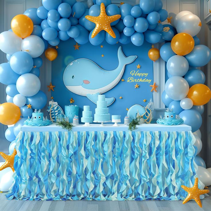 a blue and gold birthday party with balloons, stars, and a whale cake on the table