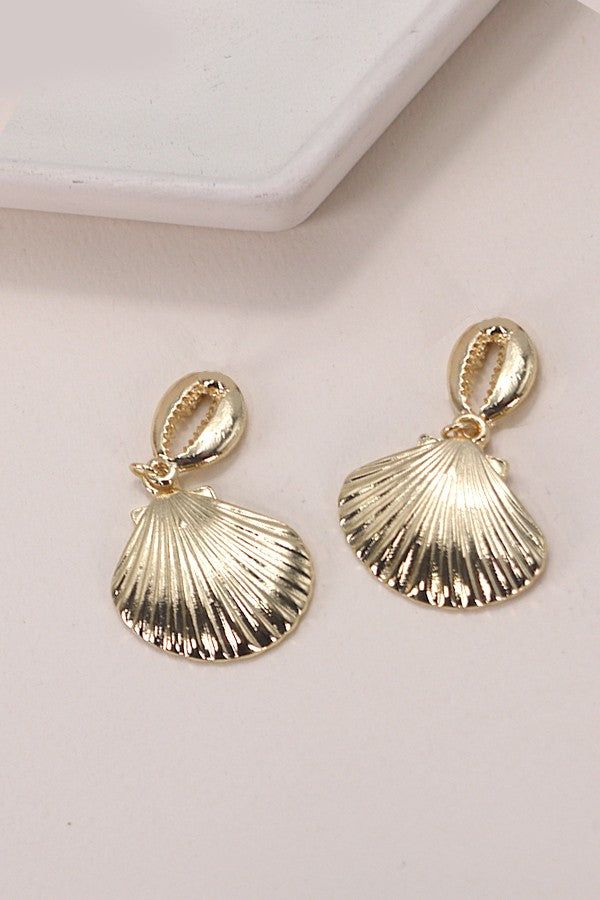 Gold Puka Seashell Drop Earrings, a stunning accessory that embodies coastal elegance. These earrings feature delicately crafted gold puka seashells, creating a chic and timeless design that seamlessly complements a variety of looks. Perfect for adding a touch of seaside allure to your ensemble, the Gold Puka Seashell Drop Earrings are versatile enough for both casual outings and more formal occasions.Product details:length: 1.5"width: 1" earring back: Postmetal finish: gold Platingproduct: Lead Gold Dangle Earrings For Beach, Gold Shell Dangle Earrings, Gold 14k Gold Filled Earrings For Beach, Gold Ocean-inspired Beach Earrings, Gold Dangle Shell Earrings, Elegant Gold Dangle Shell Earrings, Elegant Gold Dangle Shell, Gold Shell-shaped Metal Earrings, Gold Plated Shell-shaped Earrings