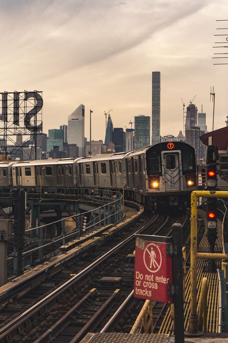 two trains on tracks with city skyline in the backgrouund and stop sign