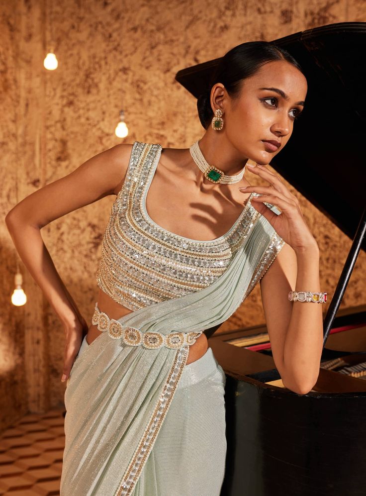 Elevate your style with this aqua drape sari, showcasing intricate embroidery on the sari border. The fully embroidered blouse steals the spotlight, and the outfit is both padded and secured with a hook-eye closure on the back, ensuring a perfect fit. Embrace the grace and charm of this ensemble, where every detail is thoughtfully crafted for a timeless appeal. Bollywood Style Embellished Festive Pre-draped Saree, Fitted Pre-draped Saree With Intricate Embroidery For Festivals, Designer Party Wear Blouse With Intricate Embroidery, Party Wear Saree Blouse With Intricate Embroidery, Elegant Fitted Pre-draped Saree With Mirror Work, Festive Party Wear Pre-draped Saree With Intricate Embroidery, Elegant Designer Pre-draped Saree In Chinon, Elegant Embellished Saree Blouse Piece, Party Wear Pre-draped Saree With Zari Work