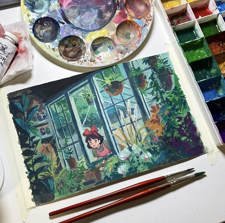 an artist's palette with paint and brushes on it next to a plate full of watercolors