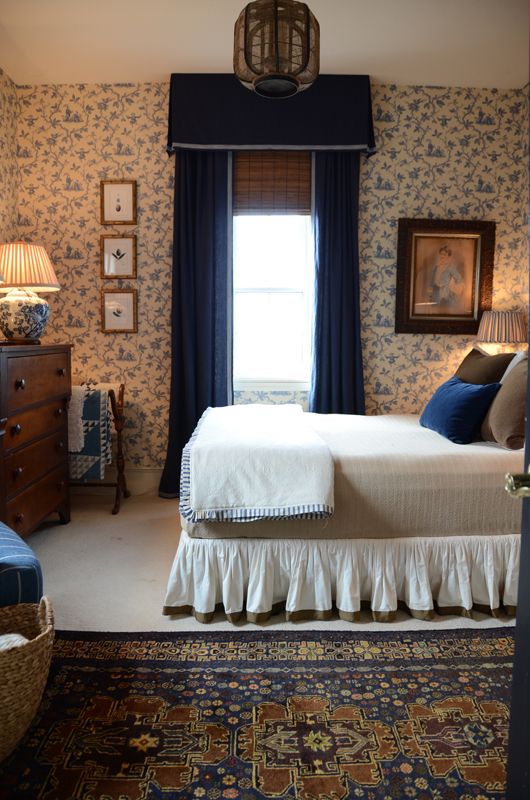 a bed sitting in a bedroom next to a window covered in blue and white wallpaper