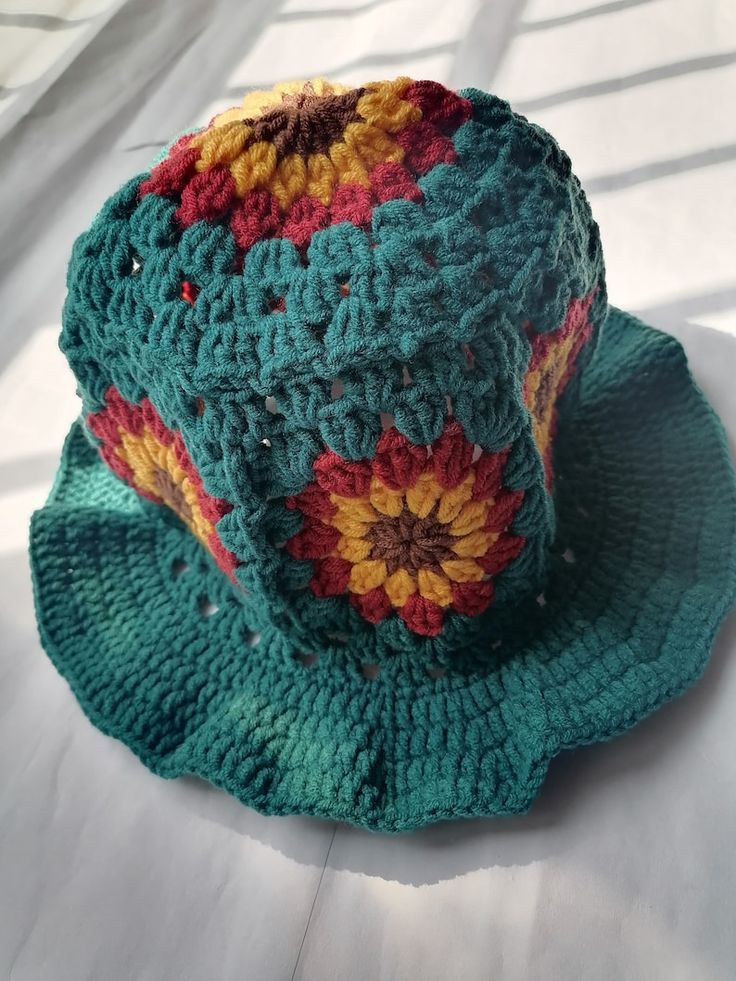 a green crocheted hat sitting on top of a bed