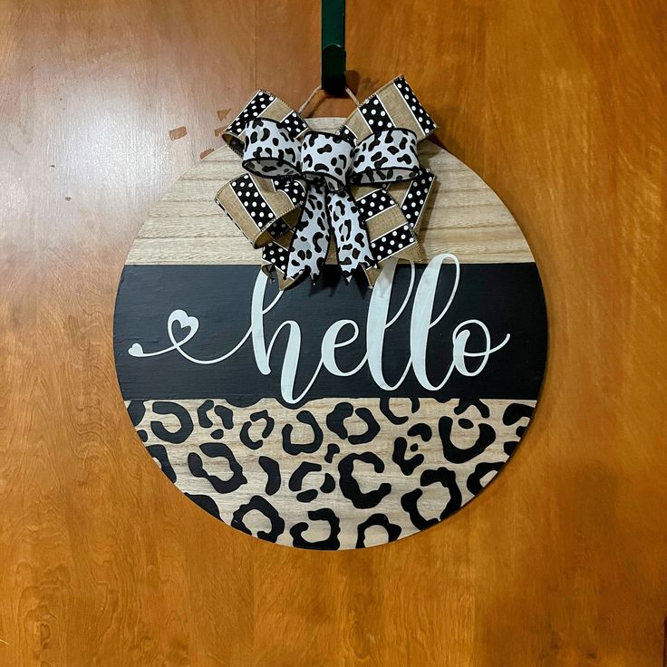 a door hanger that says hello with a leopard print bow on the front and back