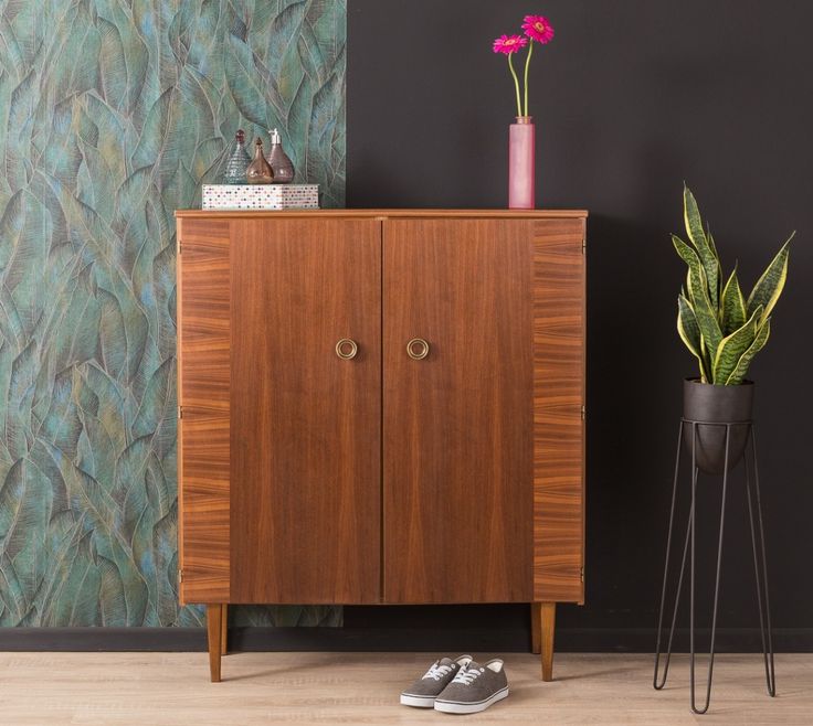 a wooden cabinet sitting next to a potted plant