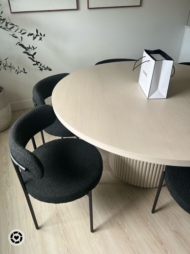 three chairs around a round table with a white box on it's head and one black chair at the end