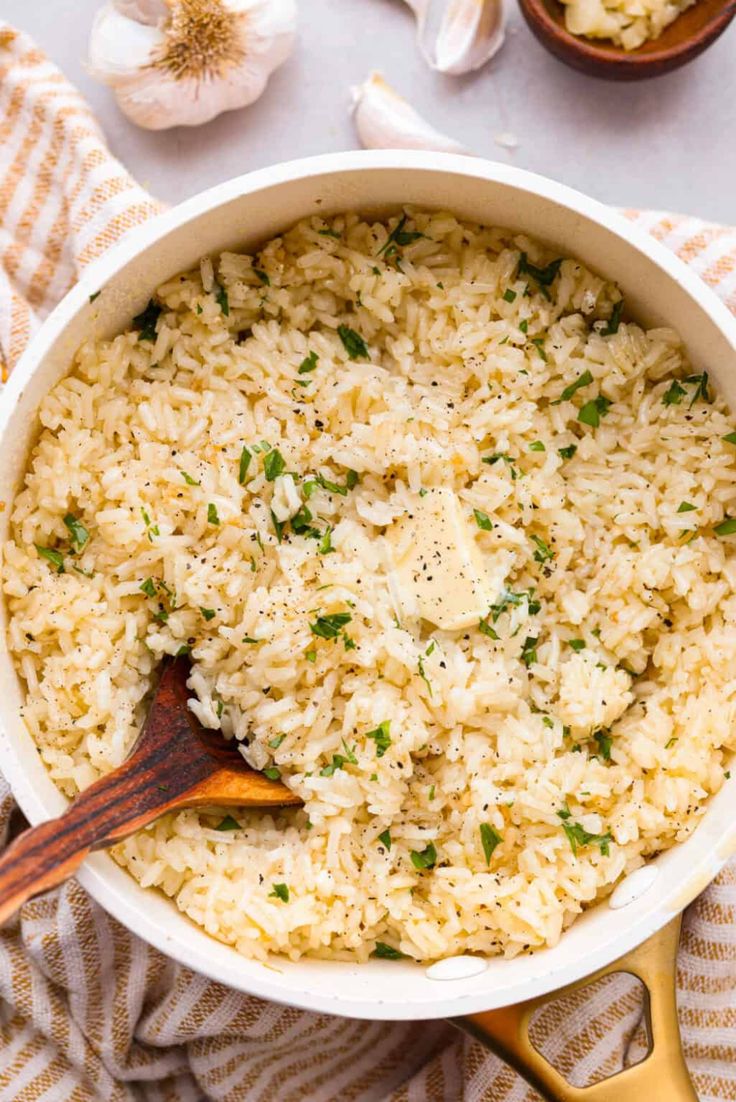 a pot filled with rice and herbs on top of a towel next to garlic florets