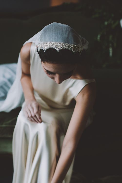 a woman in a white dress sitting on a couch wearing a tiara and veil