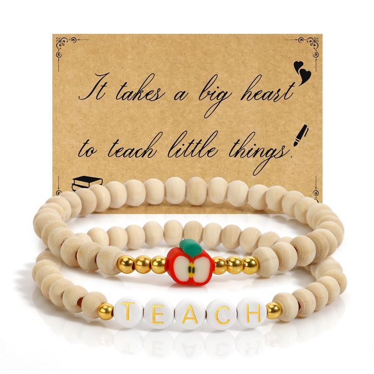 two white and gold beaded bracelets with an apple charm on each one, in front of a card that says it takes a big heart to teach little things