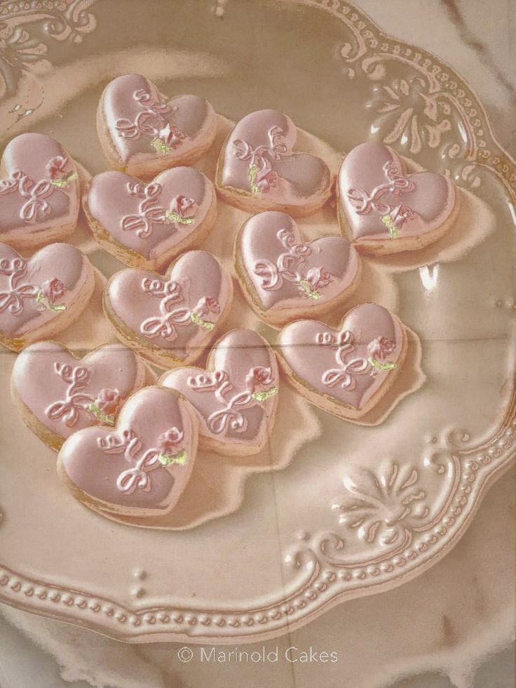 heart shaped cookies are on a plate with pink icing and embellishments