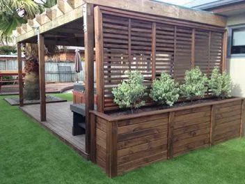 a wooden deck with plants on it and an awning over the top that is made out of wood slats