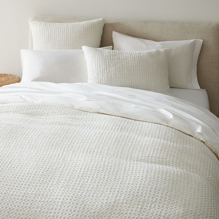 an unmade bed with white linens and pillows