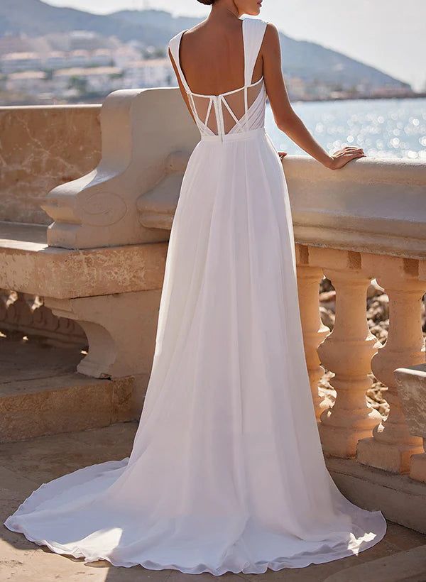 a woman in a white wedding dress standing on some steps looking at the water and mountains