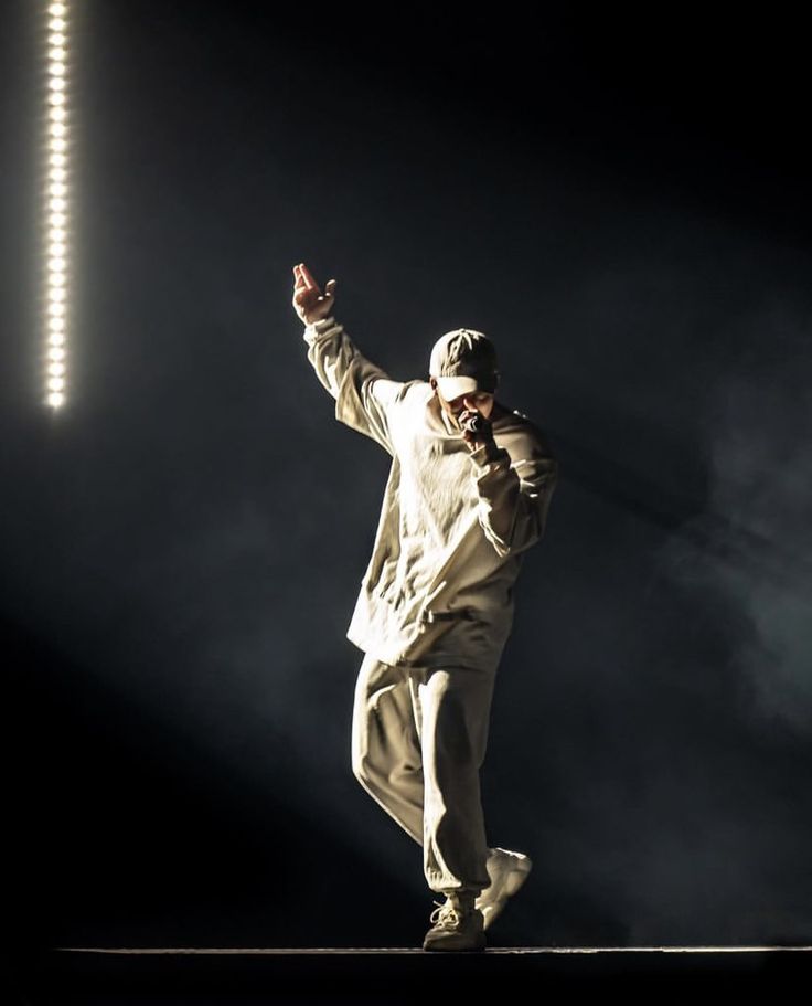 a man standing on top of a stage with his hands in the air while wearing a white suit