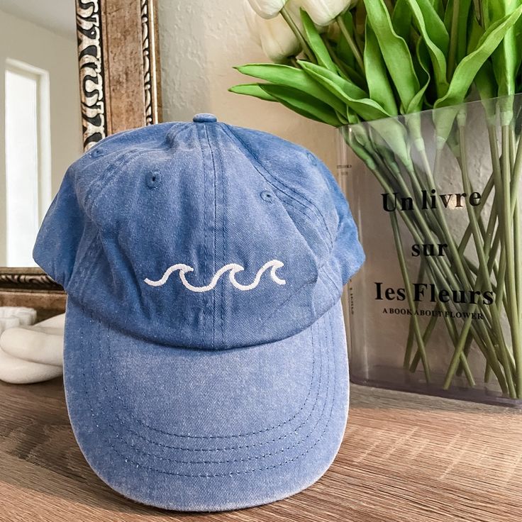 a blue hat sitting on top of a wooden table next to a vase with flowers