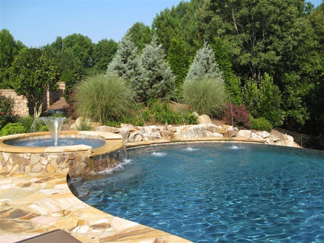 a large pool surrounded by rocks and water features a waterfall that flows into the pool