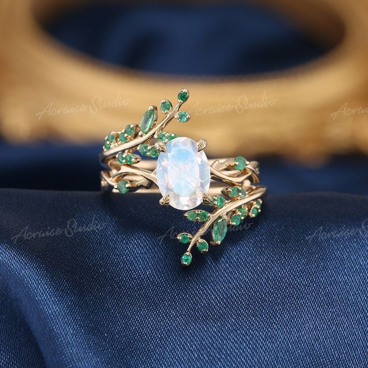 a white ring with green leaves and a blue topazte stone in the center