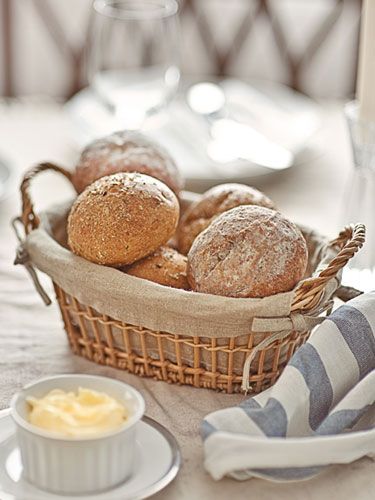 a basket filled with bread sitting on top of a table next to a bowl of butter