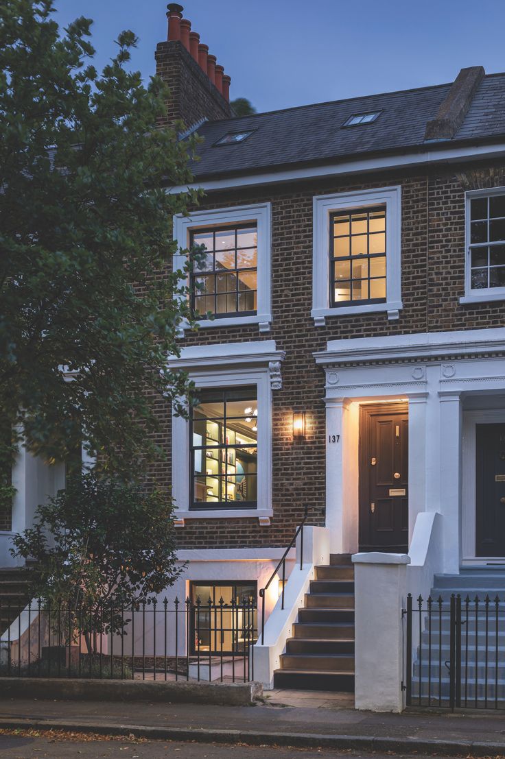 a house with stairs leading up to the front door and two story brick building at night