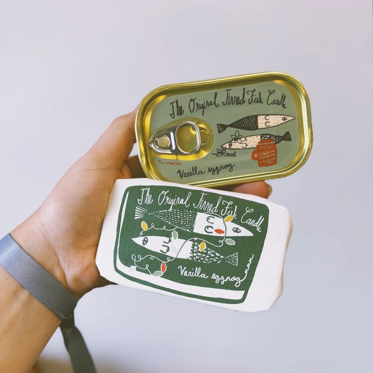 a person holding an open tin with scissors and magnets on it's side