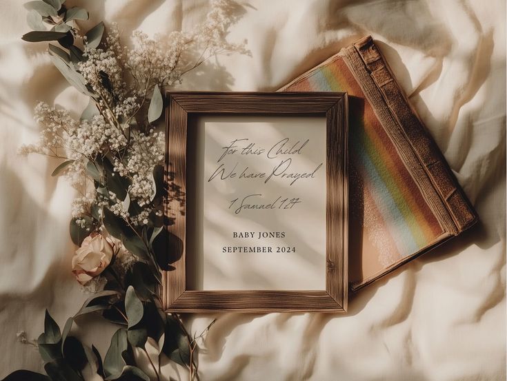 two framed pictures sitting on top of a bed next to flowers and a rainbow striped pillow