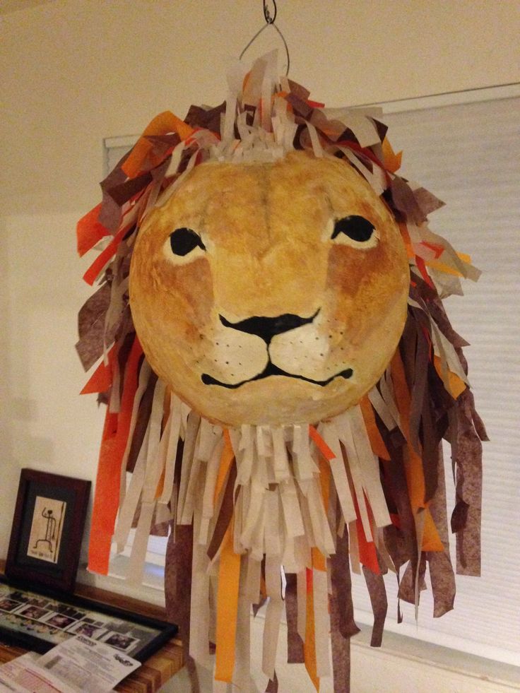 a paper mache lion head hanging from the ceiling with newspaper strips on it's face