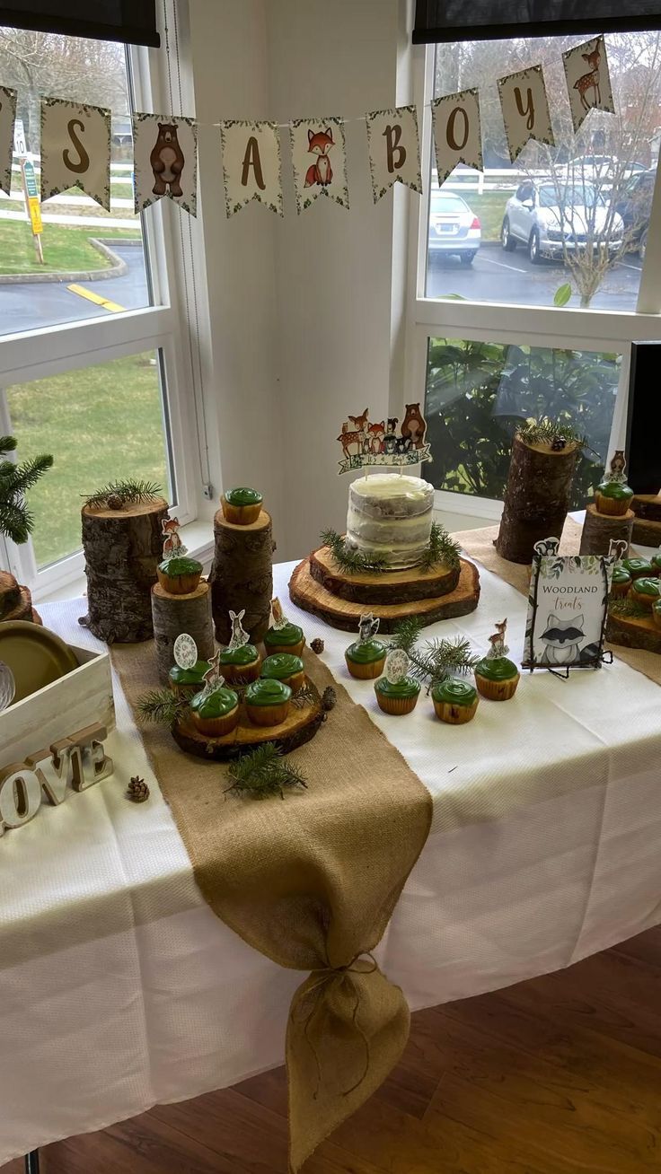 a table topped with cakes and cupcakes next to a window