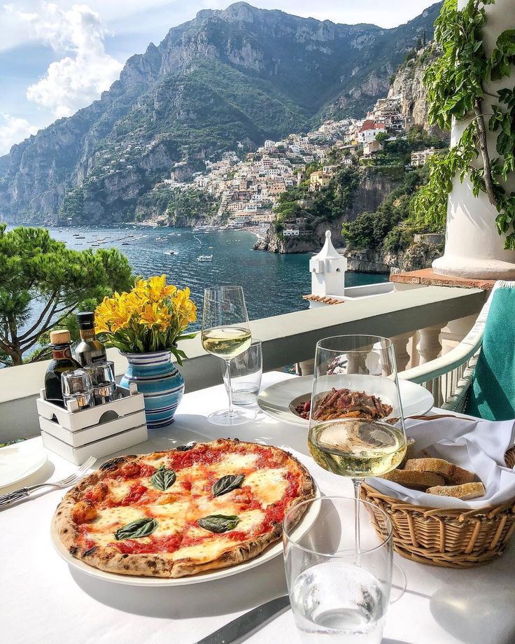 a table topped with a pizza next to a bottle of wine and plates of food