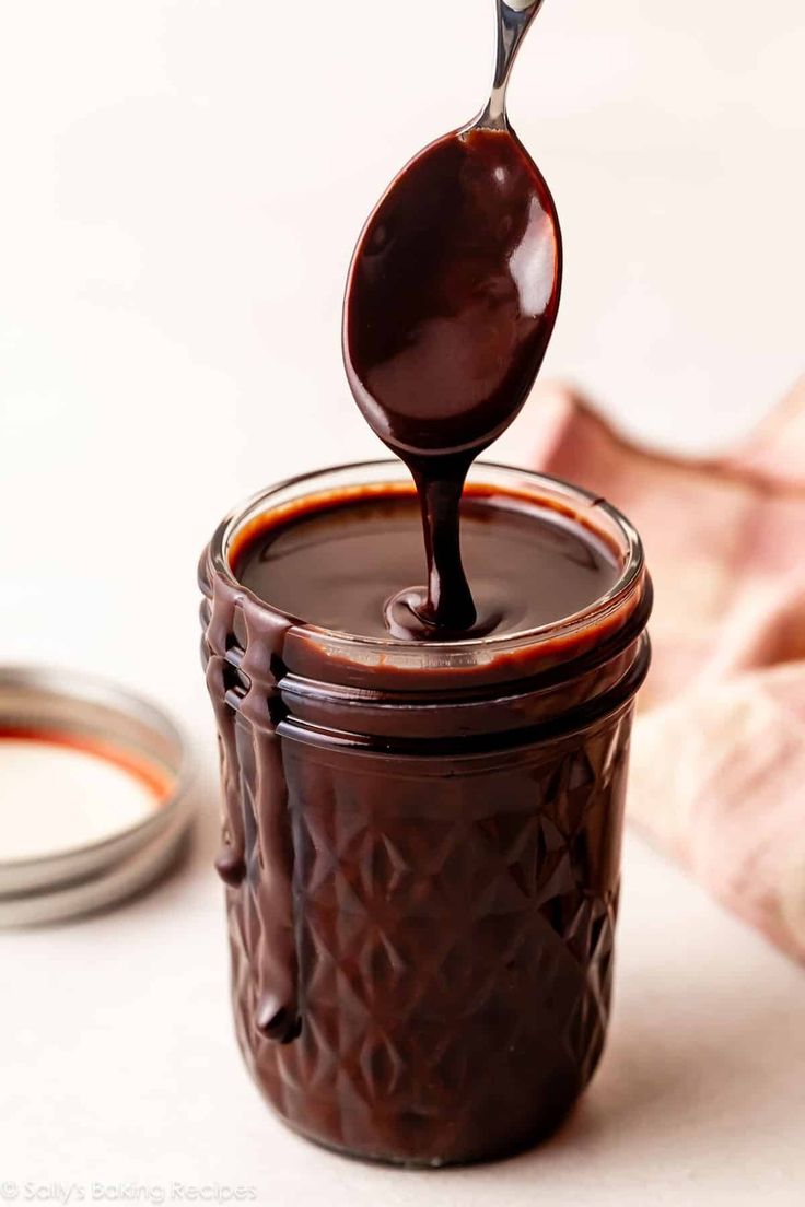 a spoon is pouring chocolate into a jar