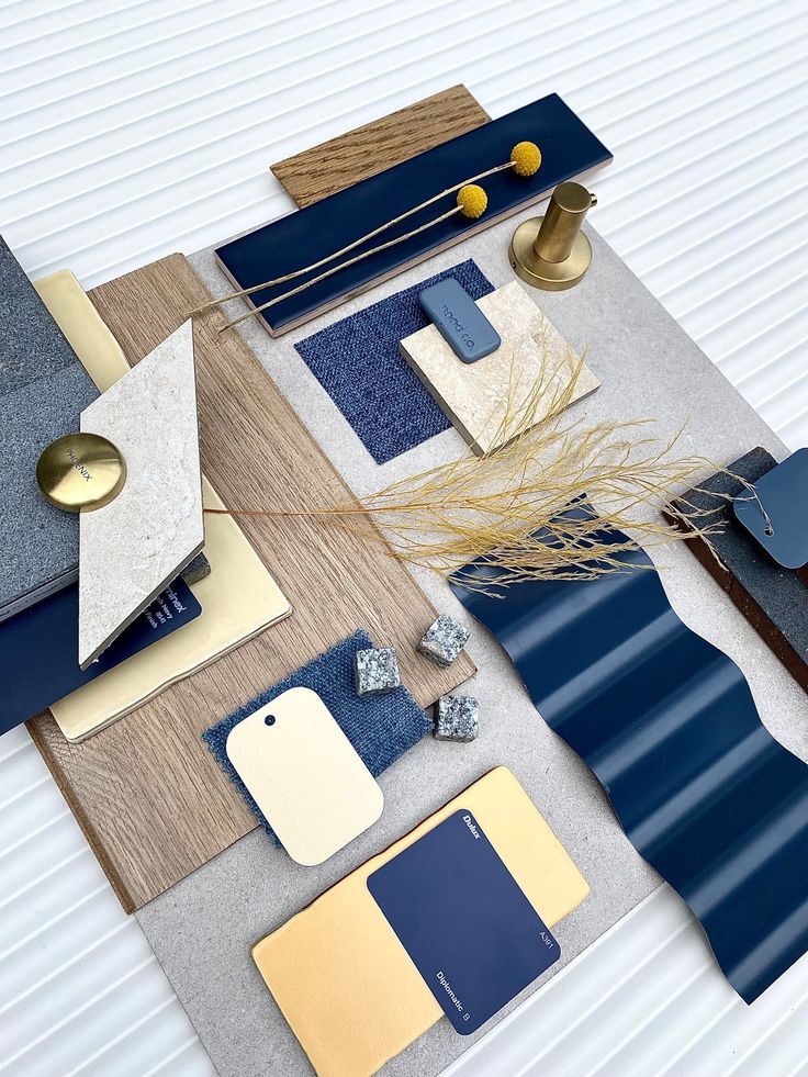 an assortment of blue, yellow and grey materials on a white surface with gold accents