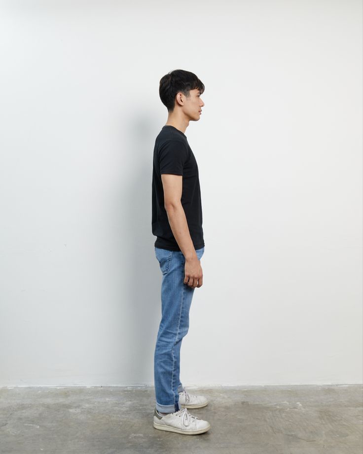 a man standing in front of a white wall with his back turned to the camera