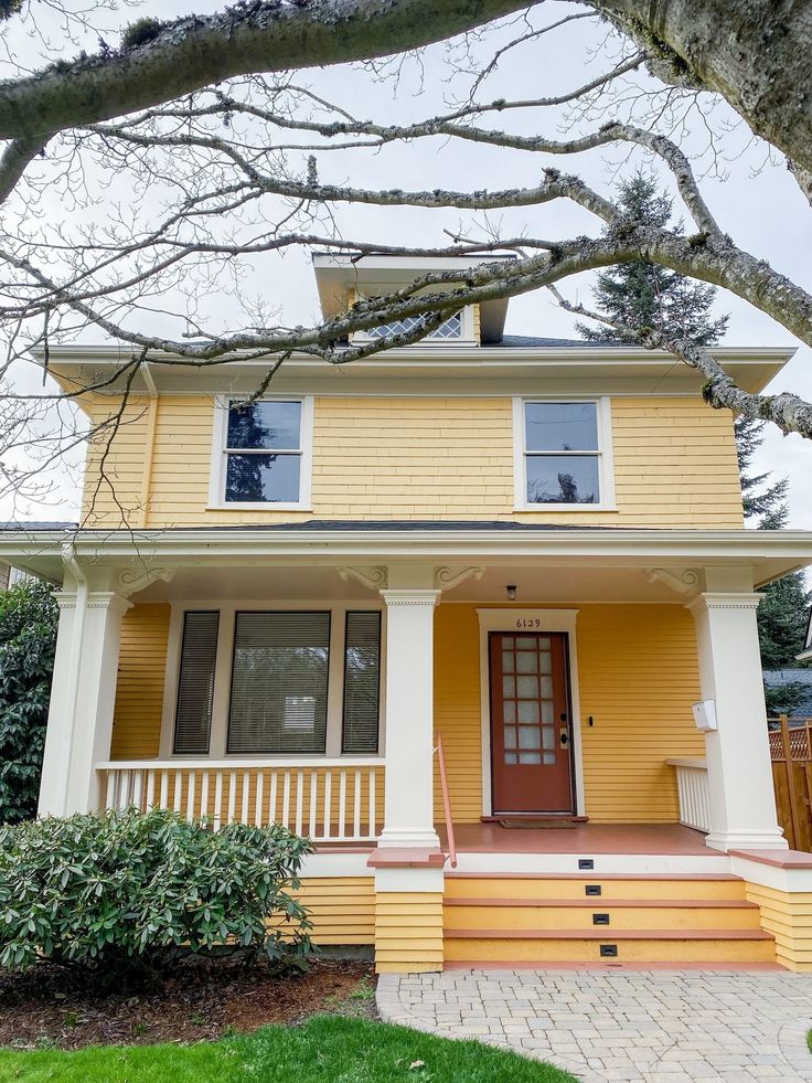 a yellow two story house with white trim on the front porch and steps leading up to it