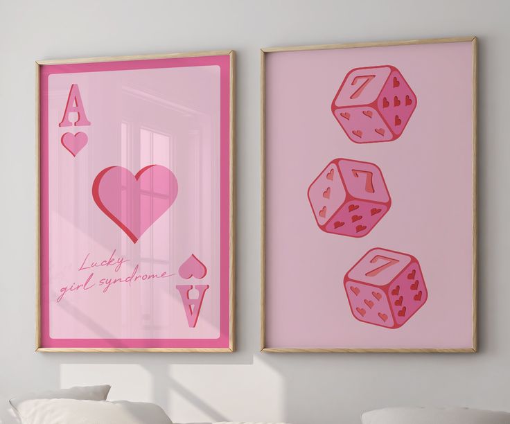 two pink framed pictures with hearts and dices on them in a white room next to a bed