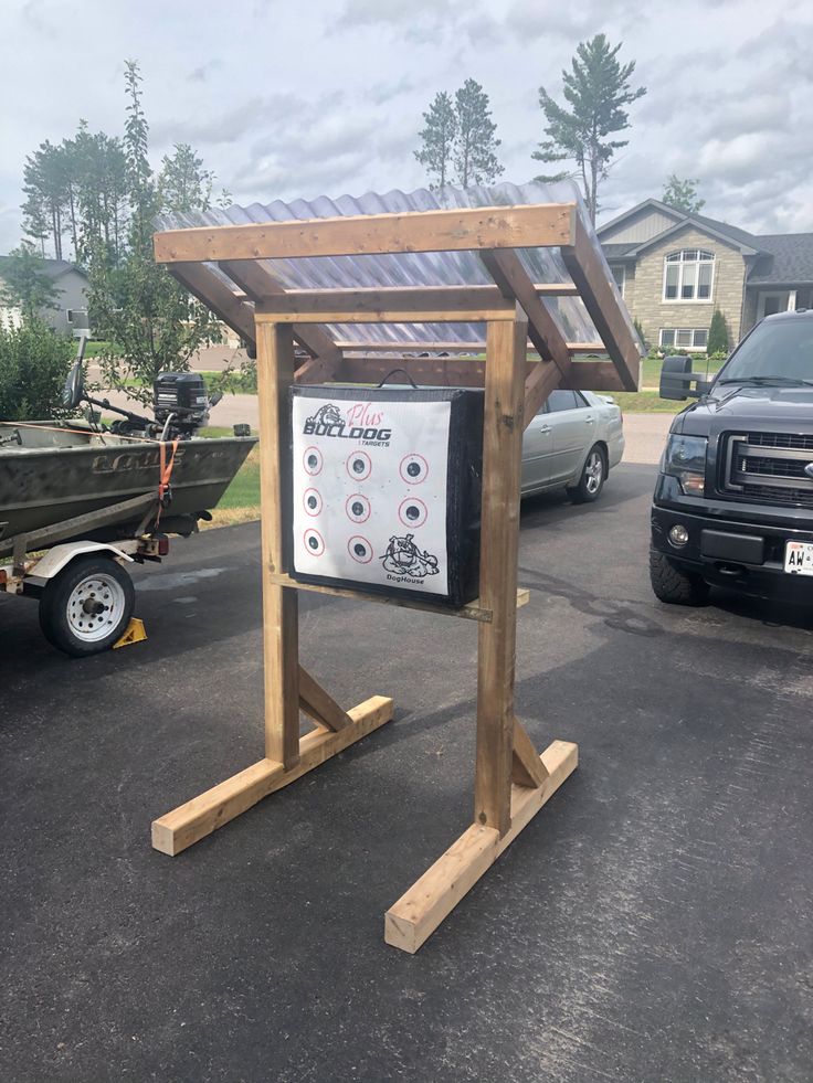 a wooden stand with a sign on it in the middle of a parking lot next to a pickup truck