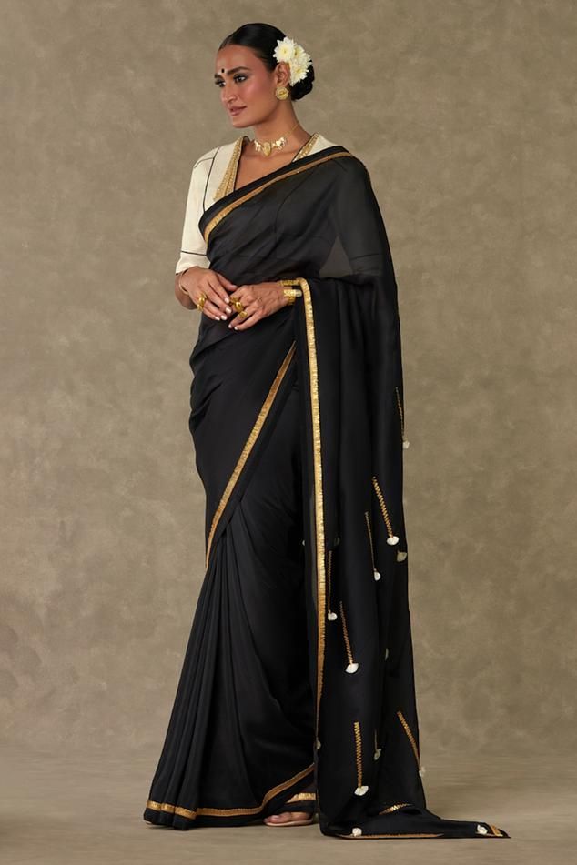 Black organza saree with contrast metallic gota and ivory fringe tassel embroidered pallu. Paired with cotton linen unstitched blouse piece.
Components: 2
Pattern: Embroidered
Type Of Work: Gota and Tassel Work
Fabric: Saree: Organza, Blouse: Cotton Linen
Color: Black
Other Details: 
Contrast kiran lace border
Note: The stitched blouse worn by the model is not for sale
Disclaimer: The actual print-placement and colour of the product may slightly vary slightly from the image shown.
Occasion: Sang Elegant Pre-draped Saree With Tassels For Festive Occasions, Elegant Wedding Saree With Tassels, Elegant Festive Saree With Tassels, Bollywood Blouse Piece With Traditional Drape And Tassels, Bollywood Blouse Piece With Tassels In Traditional Drape, Elegant Saree With Latkans For Festive Occasions, Traditional Party Saree With Tassels, Elegant Festive Saree With Latkans, Wedding Saree With Tassels