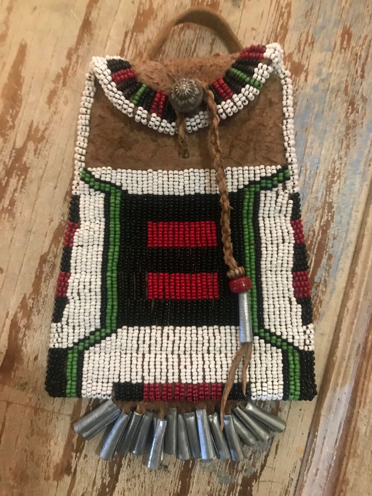 This is a beaded smoked brain tanned leather strike a light bag, in a brown colour, with beadwork in czech seed beads in white, blue , green, black, and red - and other bead embellishment.  It measures approximately 4.25" wide by 5.5" high, with 1" cones on the fringe across the bottom.  The bag is also fully lined in period fabric.  It has a leather strap on it so it can be worn on your belt, and a pewter button.    Handmade in USA! Traditional Beaded Rectangular Shoulder Bag, Unique Beaded Bags For Everyday Use, Unique Beaded Everyday Bags, Traditional Green Beaded Bag, Traditional Green Beaded Bags, Traditional Multicolor Beaded Bags, Artisan Beaded Rectangular Bag, Artisan Brown Beaded Bag, Artisan Multicolor Beaded Bags