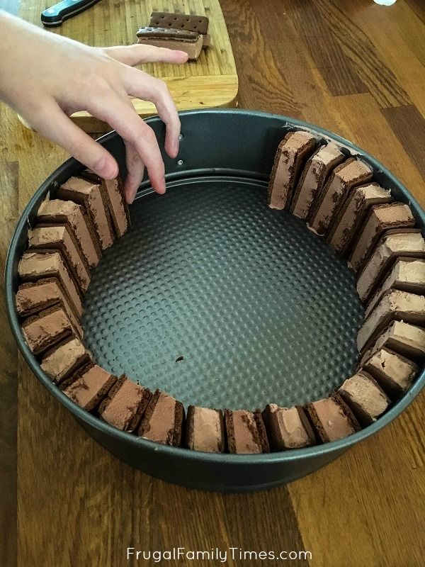 someone is decorating a chocolate cake in a pan on the table with other desserts