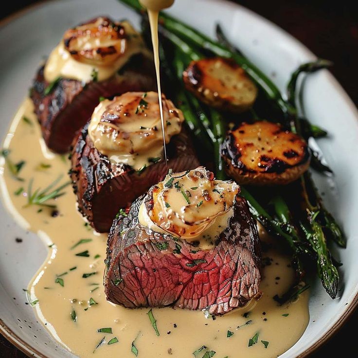 a plate with steak, potatoes and asparagus is being drizzled with sauce