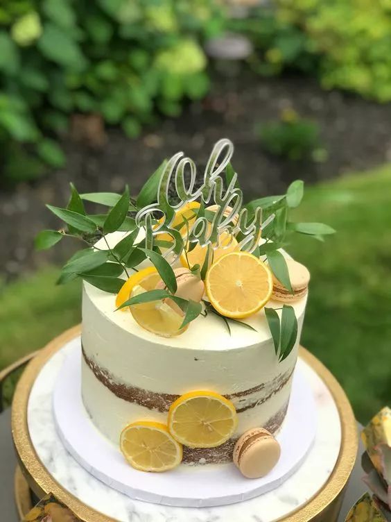 a white cake with lemons and greenery on top