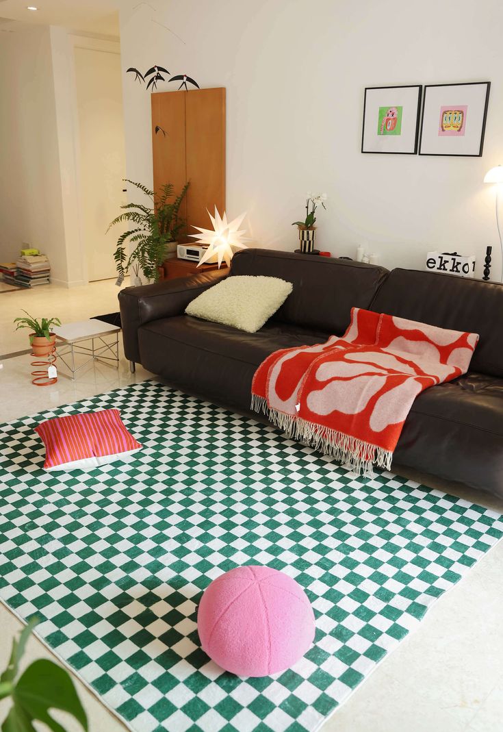 a living room with black and white checkered flooring, pink throw pillow on the rug